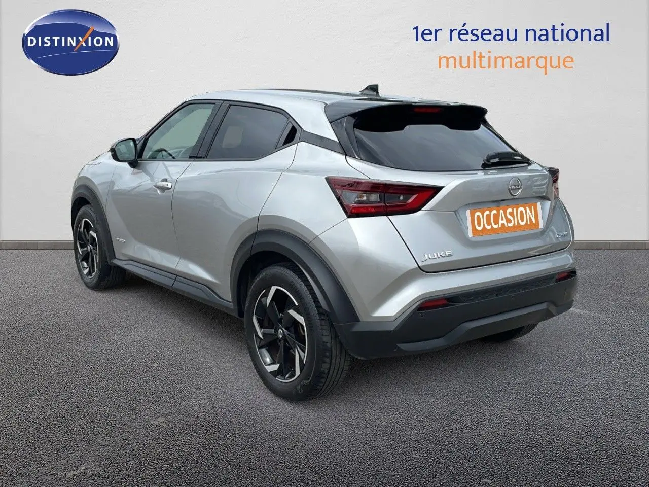 Vue 3/4 arrière droite d'un Nissan Juke hybride gris perle métal avec jantes noires et toit noir.