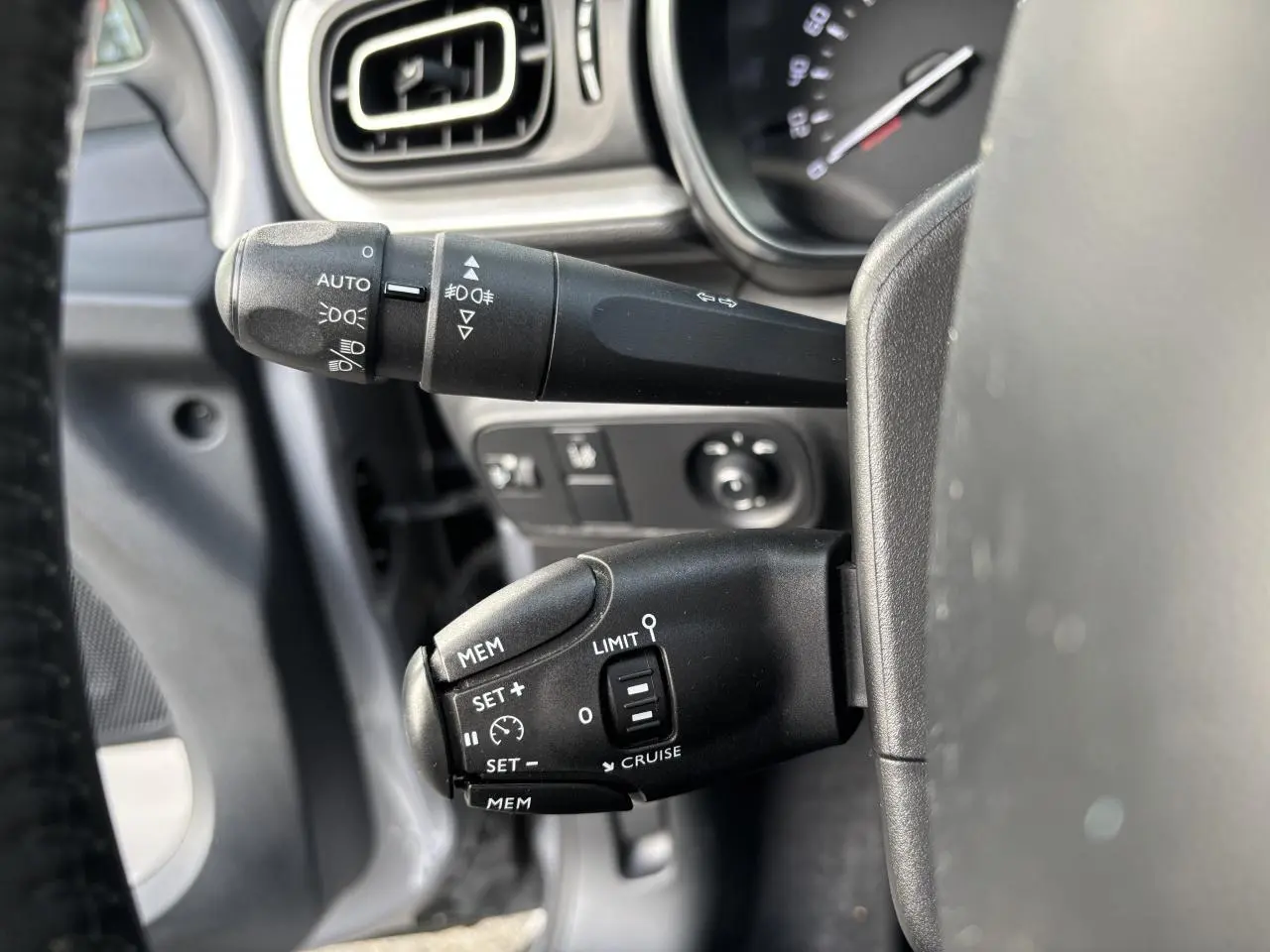 Gros plan sur les commandes au volant de la Citroën C3 2019, avec réglages du régulateur et des feux visibles.
