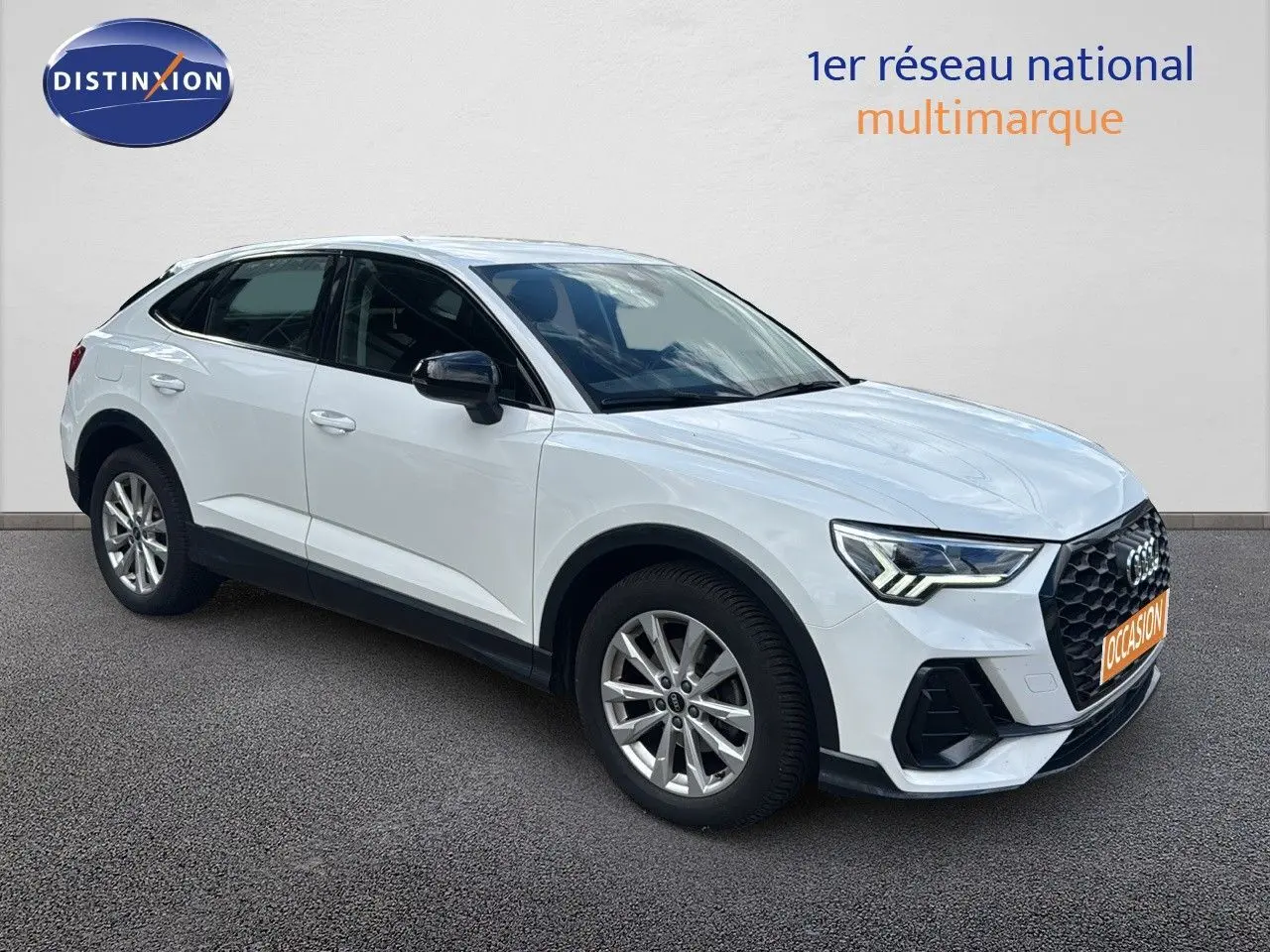 Audi Q3 Sportback blanc en 3/4 avant droit, avec calandre noire et jantes alliage visibles.