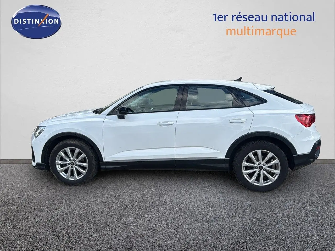 Profil côté gauche d'un Audi Q3 Sportback blanc de 2021 avec jantes alliage et toit plongeant distinctif.