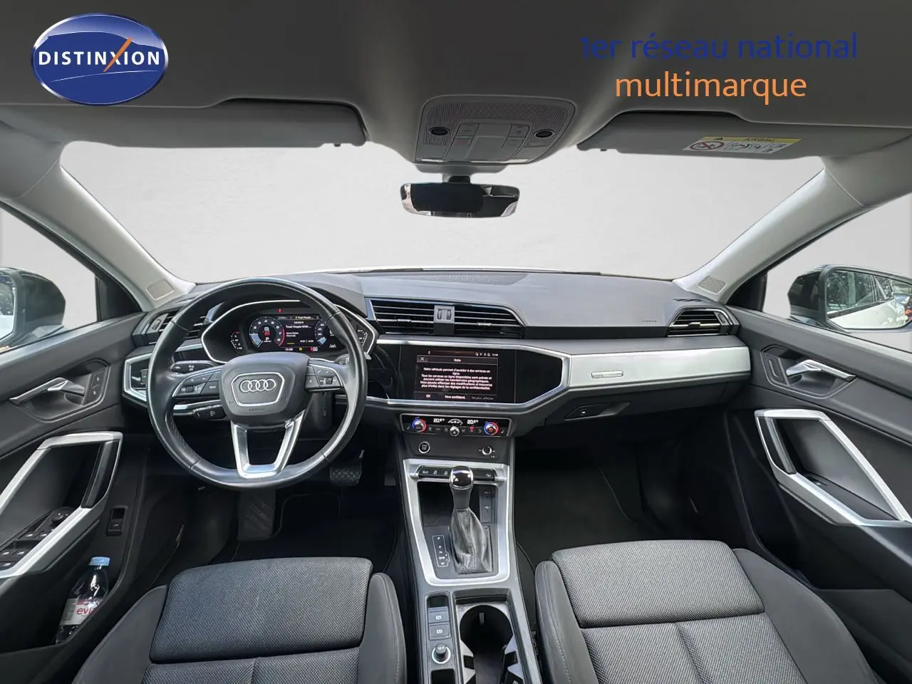 Vue intérieure avant de l'Audi Q3 Sportback 2021, tableau de bord moderne avec écran tactile et volant multifonction noir.