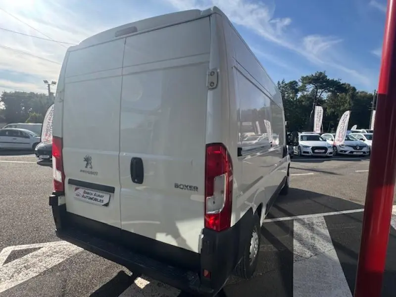 Vue 3/4 arrière droite du Peugeot Boxer Fourgon blanc banquise avec portes battantes arrière fermées sur parking.