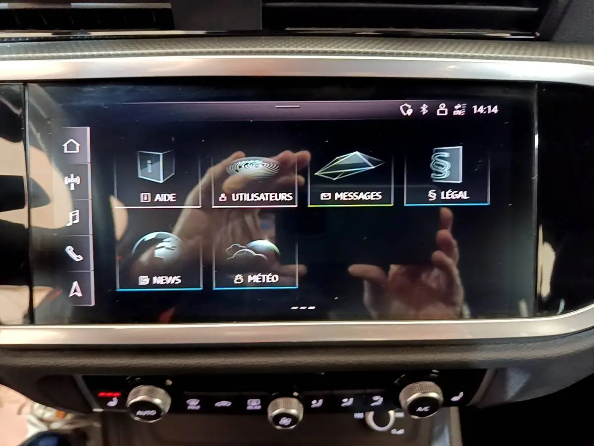 Écran tactile central de l'Audi Q3 gris foncé, affichant le menu principal avec options d'aide et messages.