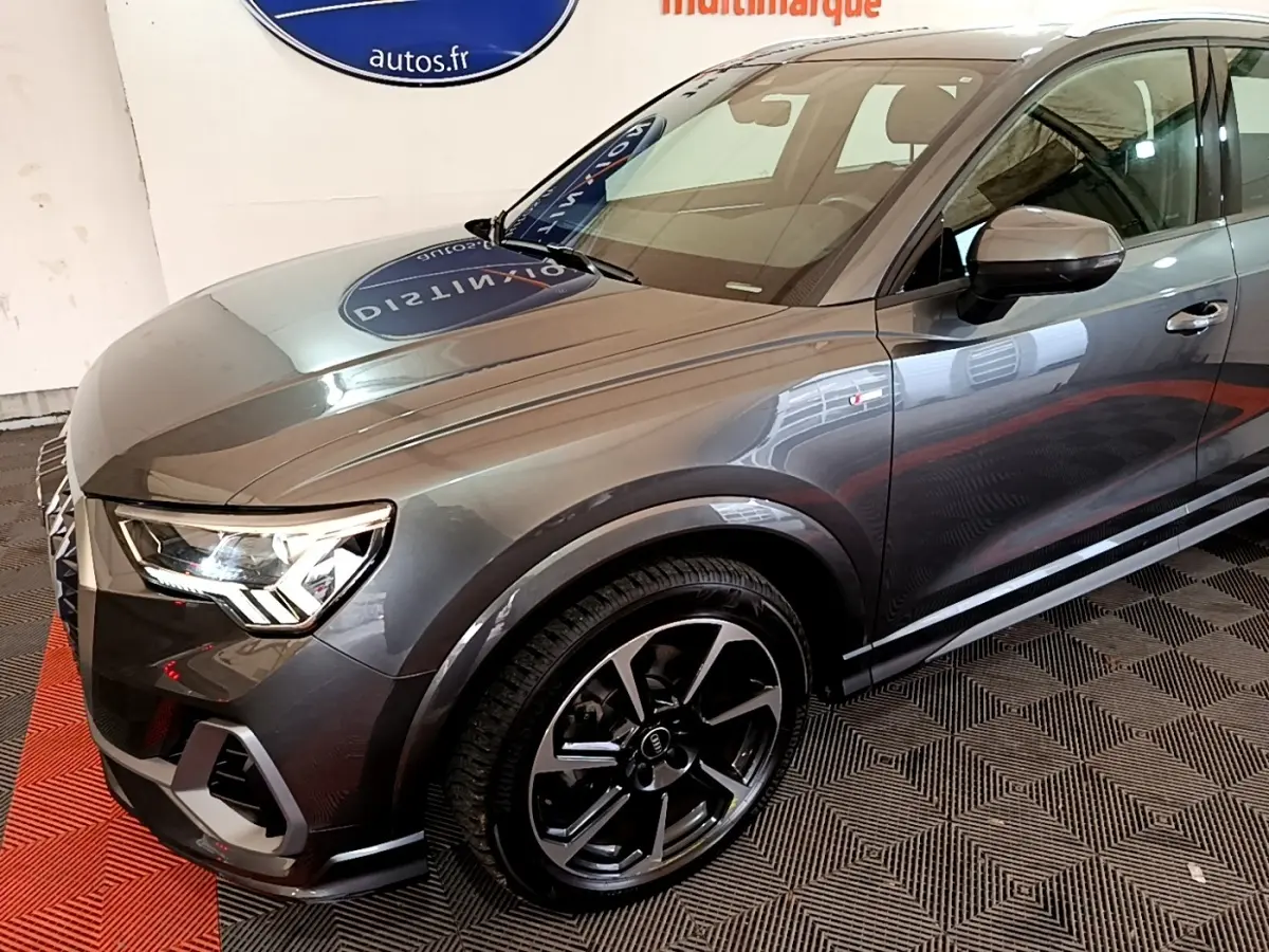 Audi Q3 gris foncé vue 3/4 avant droit, mettant en valeur ses phares LED et jantes noires distinctives.