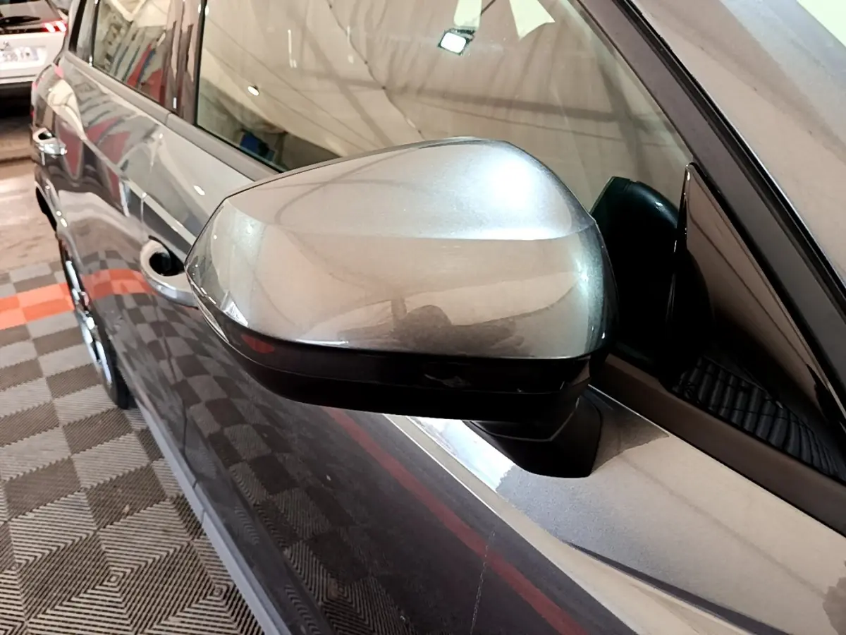 Rétroviseur côté gauche gris foncé d’un Audi Q3 35 TFSI S Line 2022, vue rapprochée en intérieur de garage.