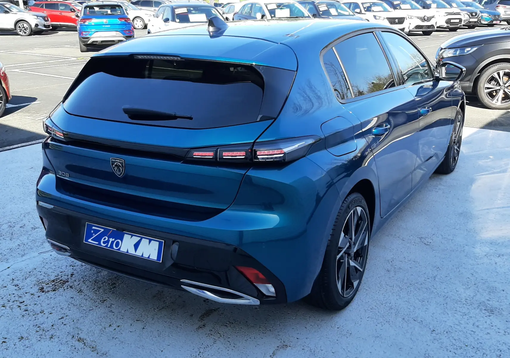 Vue arrière d'une Peugeot 308 bleu obsession avec feux LED étirés et double sortie d'échappement chromée.