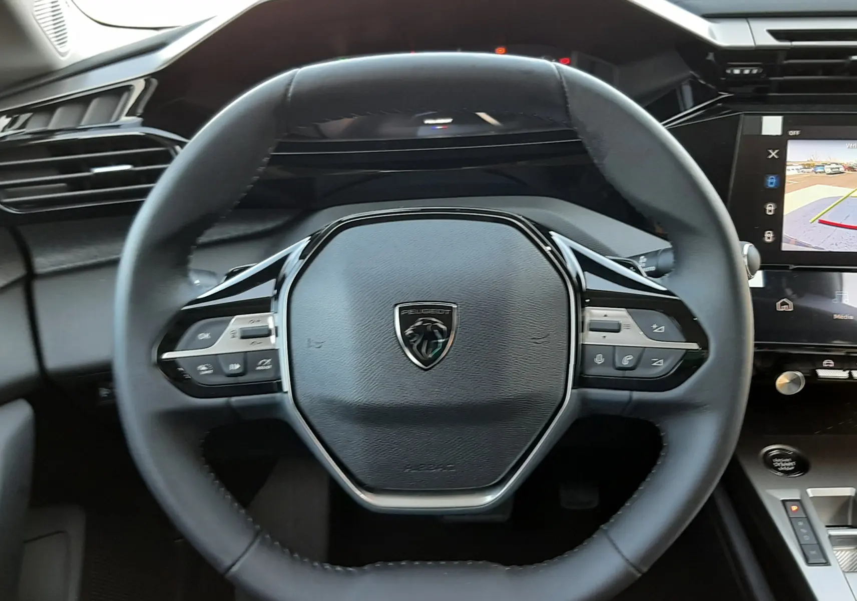 Vue intérieure centrée sur le volant et la console centrale de la Peugeot 308 2026, avec écran tactile affichant la caméra 360°.