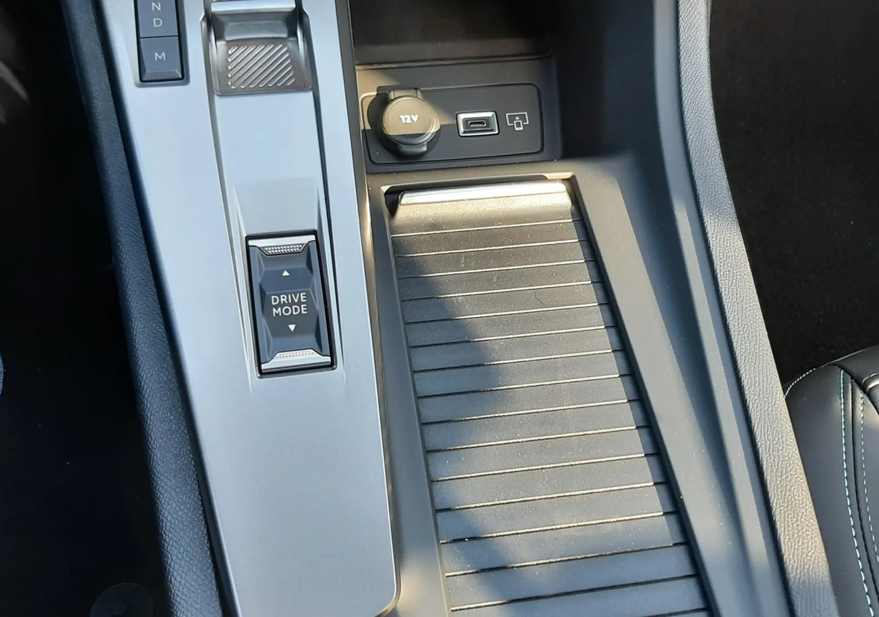 Gros plan sur le bouton de frein à main électronique rouge dans l'habitacle noir de la Peugeot 308 Bleu Obsession.