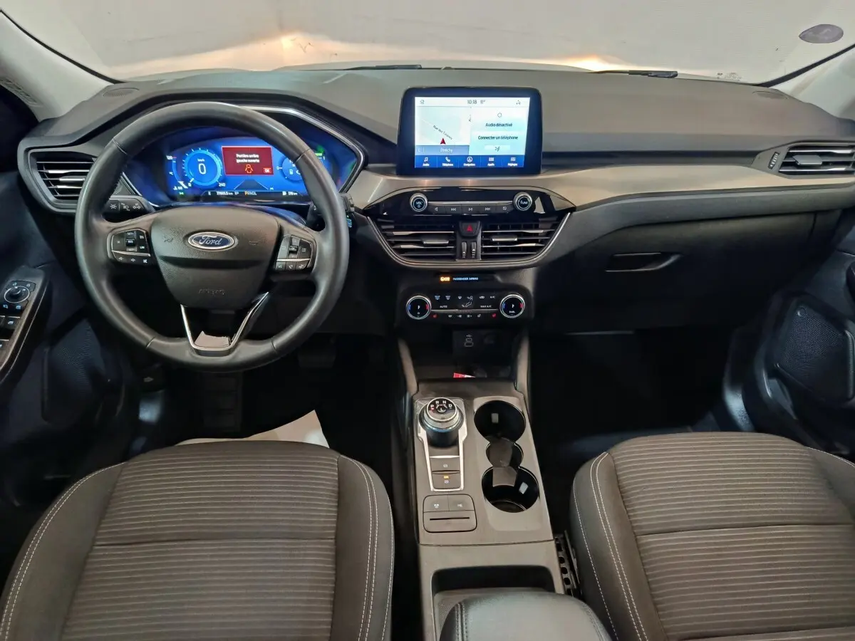 Vue intérieure frontale du tableau de bord et volant cuir du Ford Kuga 2.5 hybrid Titanium avec écran tactile central.