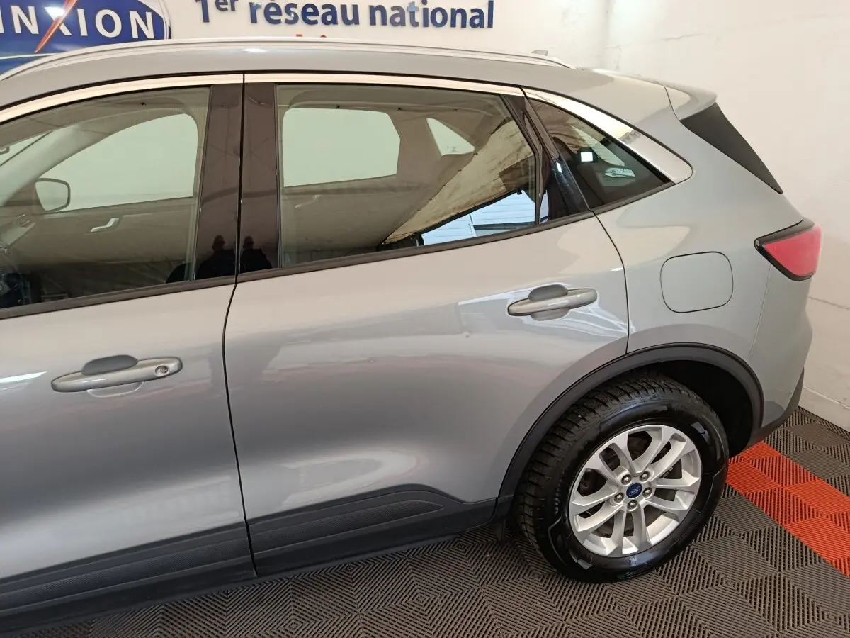 Vue latérale côté droit du Ford Kuga gris foncé 2023, mettant en valeur les portes arrière et la roue arrière.