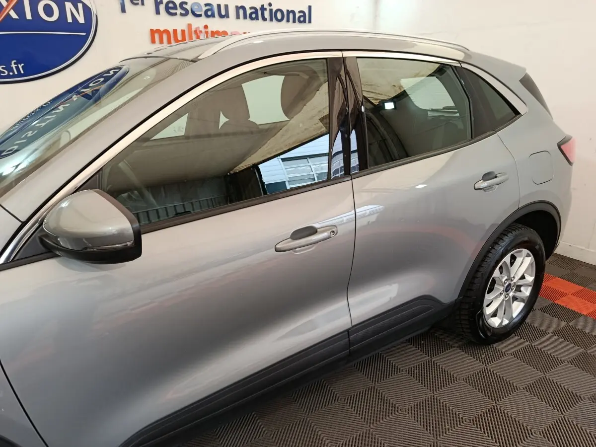 Vue latérale côté gauche d'un Ford Kuga gris foncé 2023 avec rétroviseur et poignées assortis.