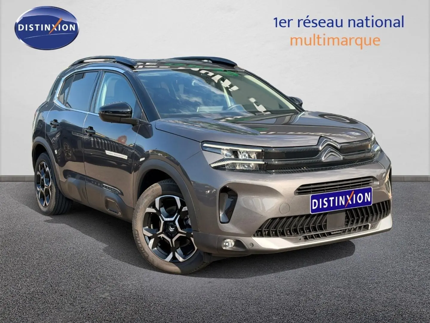 Citroën C5 Aircross gris Platinium vue 3/4 avant droit avec jantes alu et barres de toit visibles.