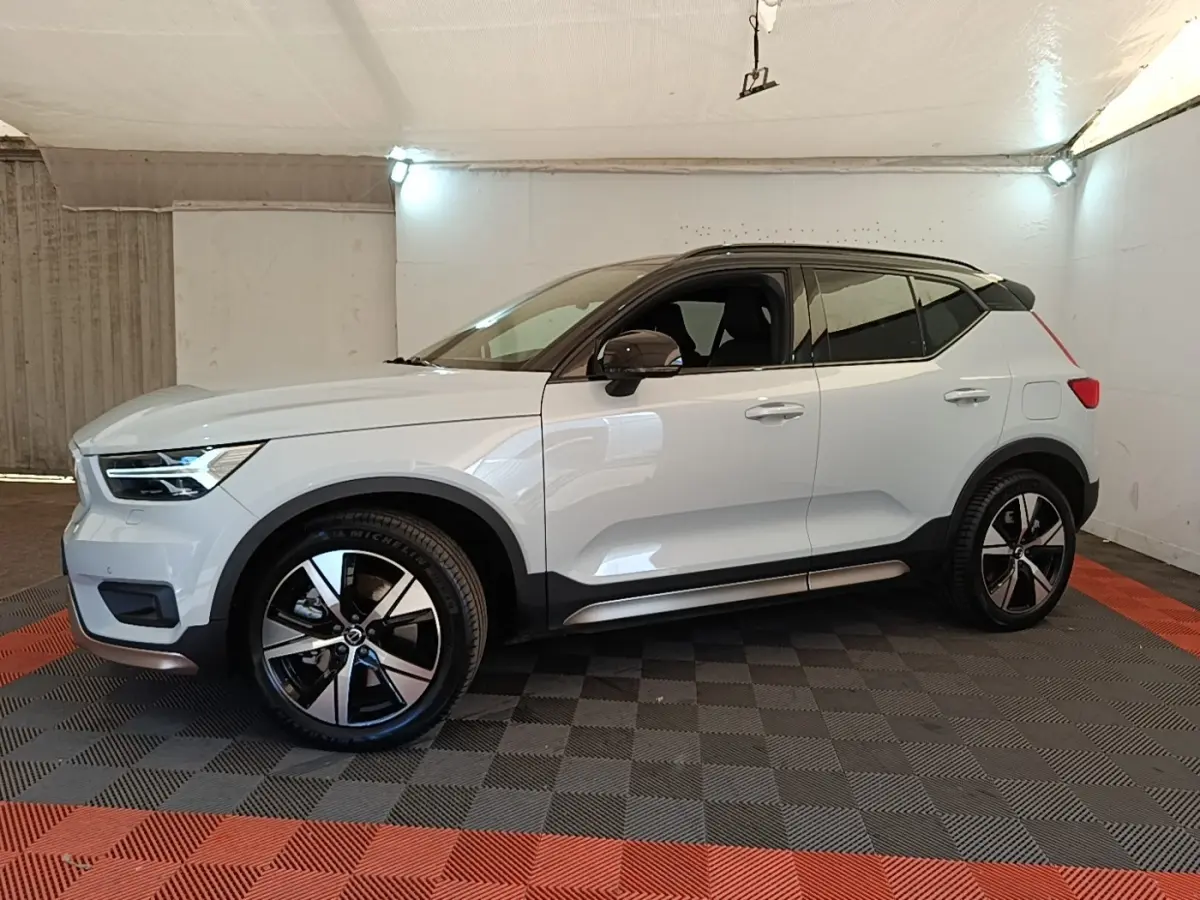 Vue de profil côté gauche d'un Volvo XC40 P8 R-Design gris clair dans un garage avec jantes noires et toit noir.