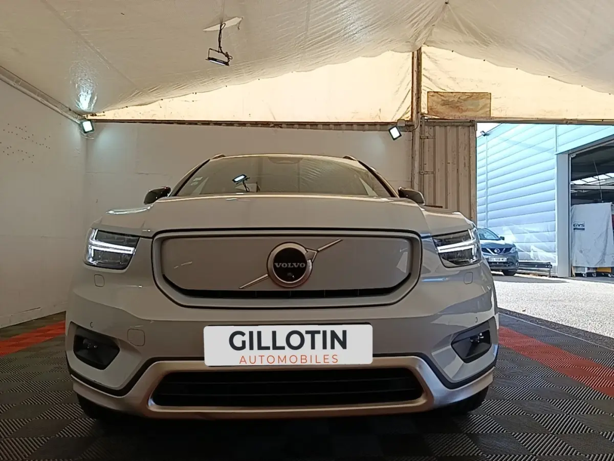 Vue frontale d'un Volvo XC40 P8 gris clair électrique avec phares LED et calandre fermée, en intérieur sous tente.