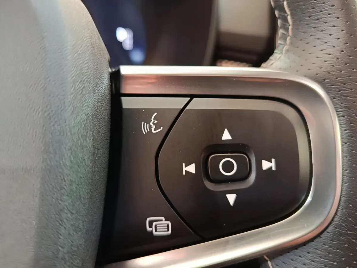 Gros plan sur les commandes vocales et de navigation du volant cuir du Volvo XC40 gris clair, version P8 R-Design.