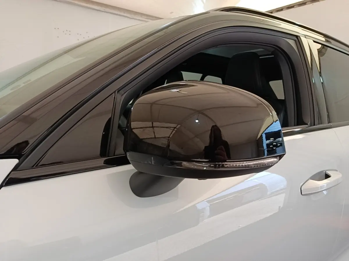 Rétroviseur noir brillant côté gauche du Volvo XC40 P8 gris clair, vue rapprochée sur la porte avant.