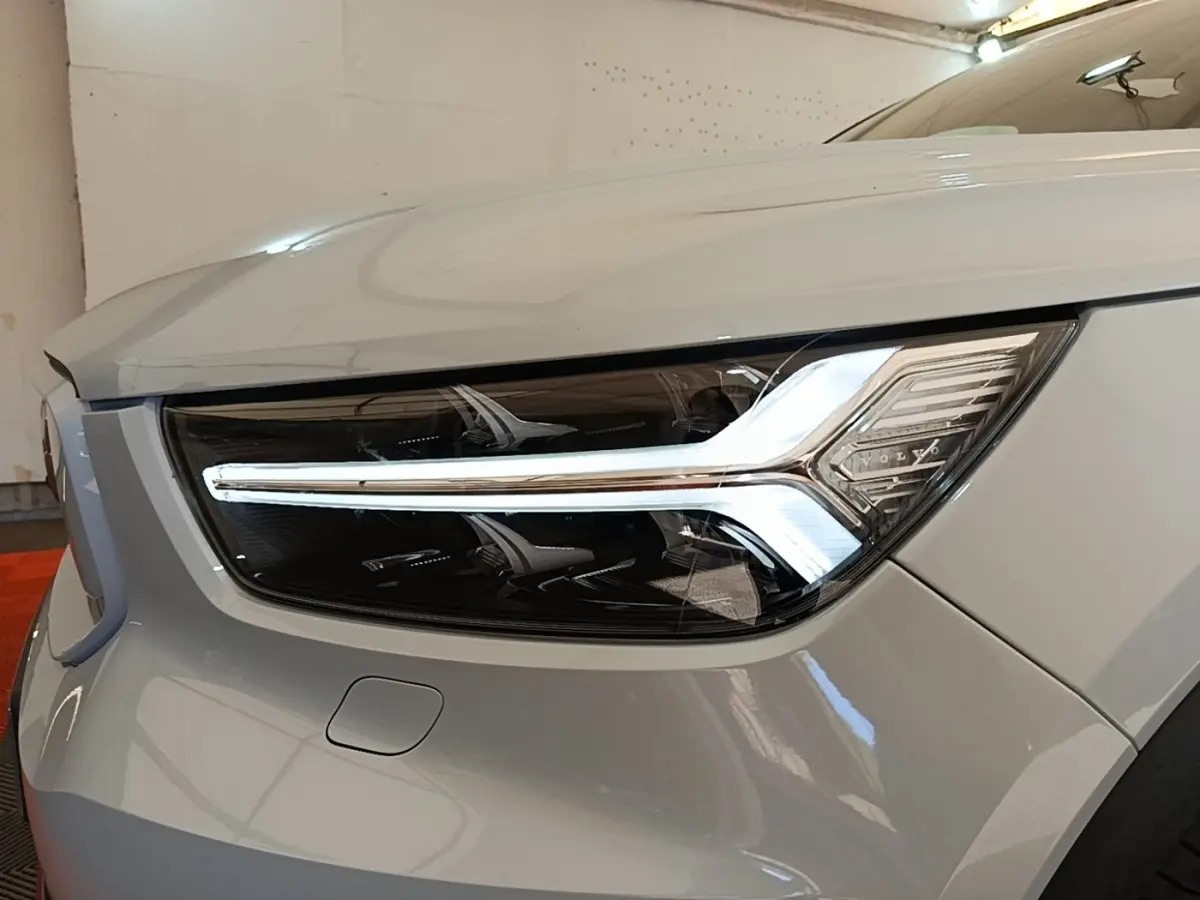 Gros plan sur le phare avant droit gris clair du Volvo XC40 P8 R-Design avec signature lumineuse LED distinctive.