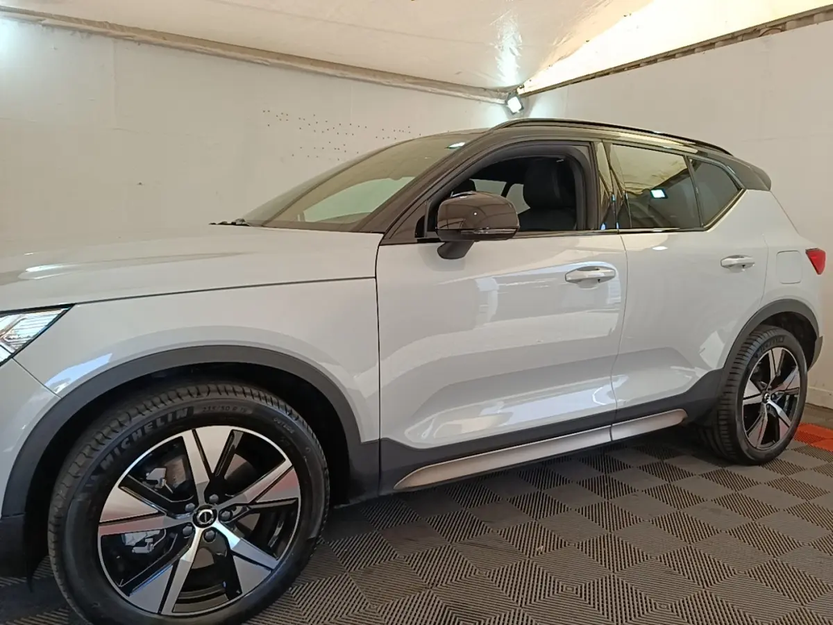Vue de profil côté gauche d’un Volvo XC40 P8 R-Design gris clair avec jantes alliage noires et toit noir.