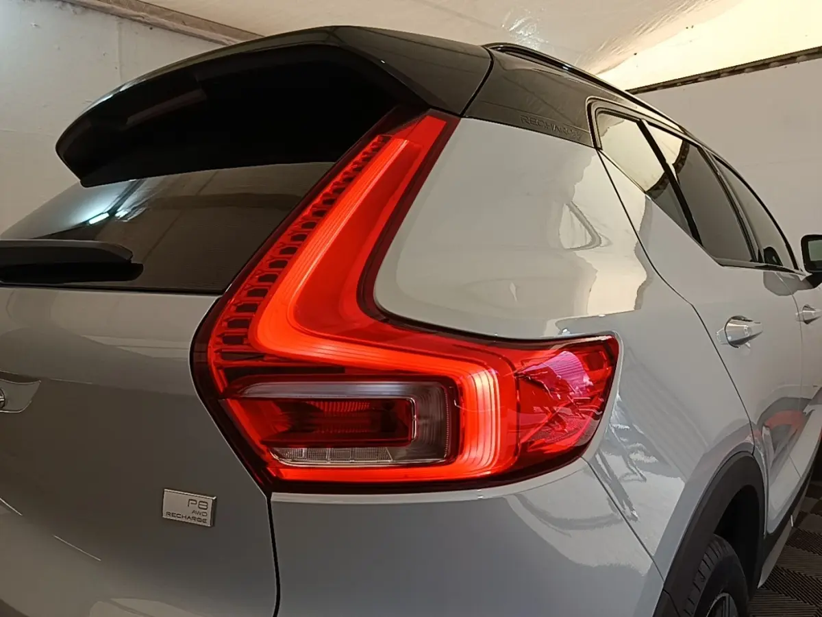 Vue 3/4 arrière droit du Volvo XC40 P8 gris clair avec feux arrière LED en forme de L et toit noir.