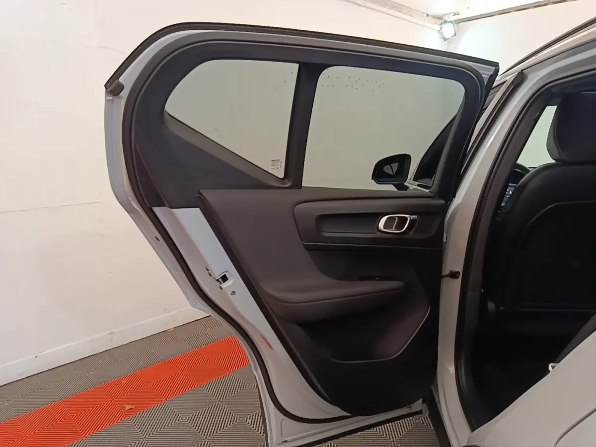 Vue côté gauche arrière du Volvo XC40 P8 gris clair avec porte ouverte, montrant l'intérieur sobre de la porte arrière.