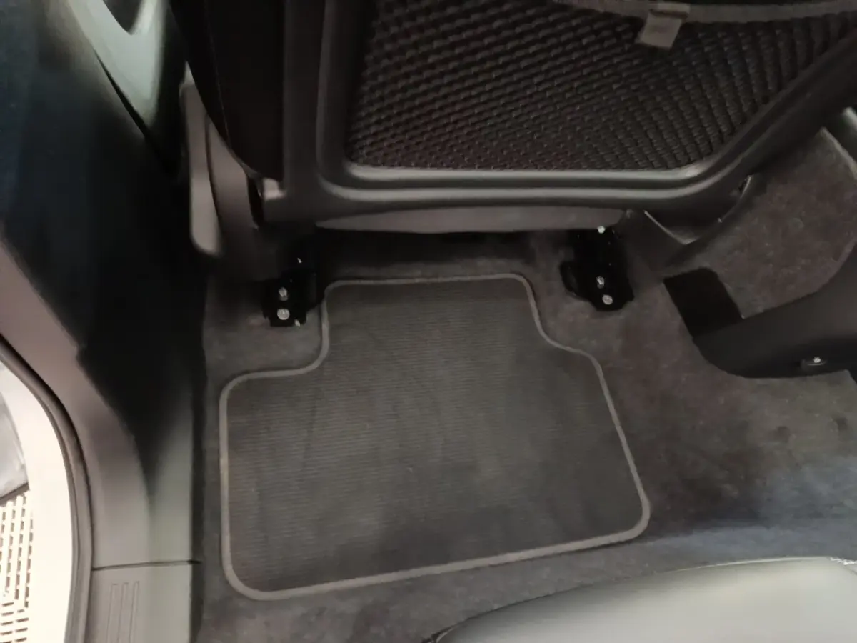 Gros plan sur le tapis de sol gris foncé sous le siège arrière du Volvo XC40 P8 408 R-Design électrique.