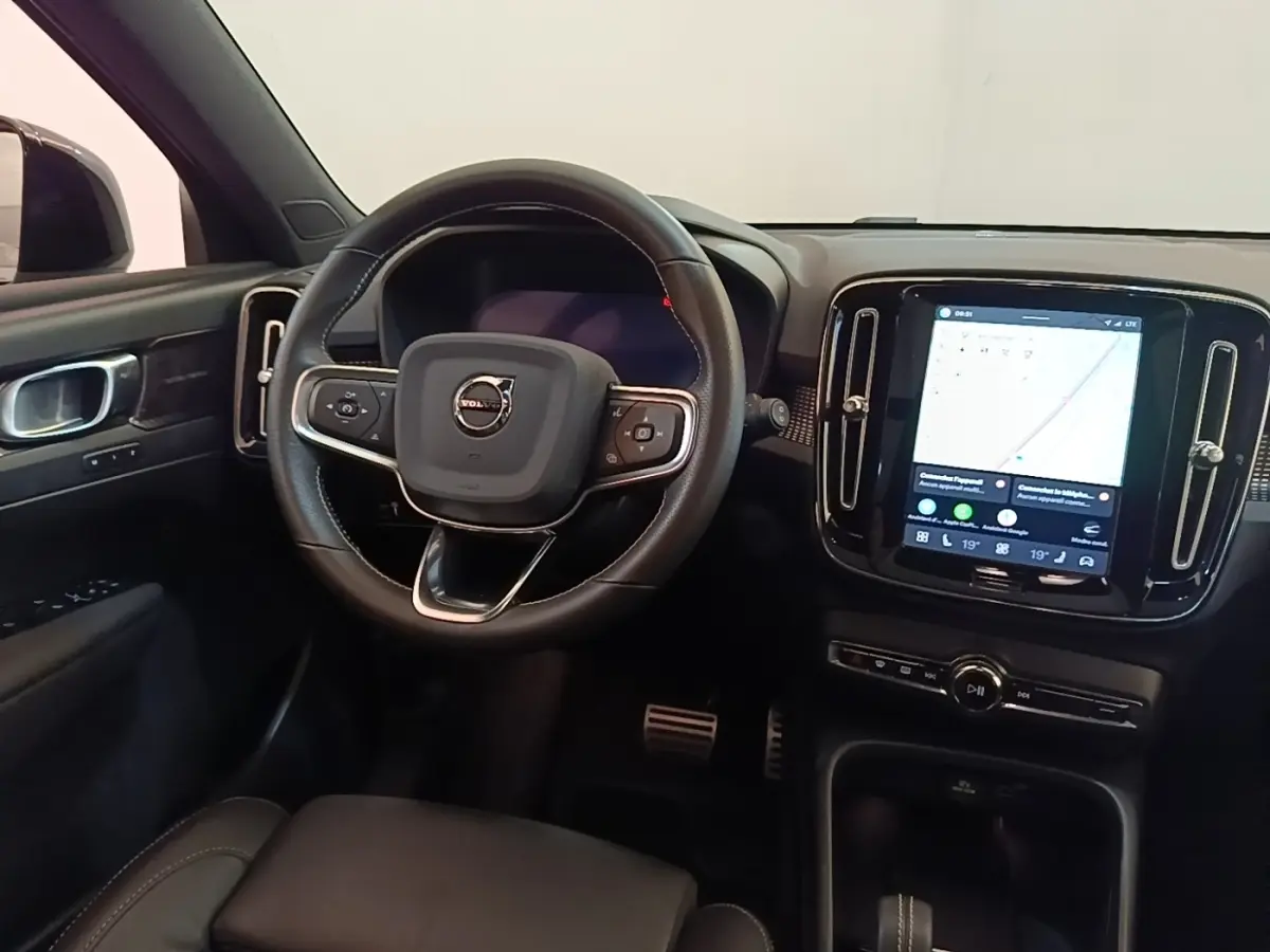 Vue intérieure du tableau de bord et volant noir du Volvo XC40 P8 électrique avec écran tactile central allumé.