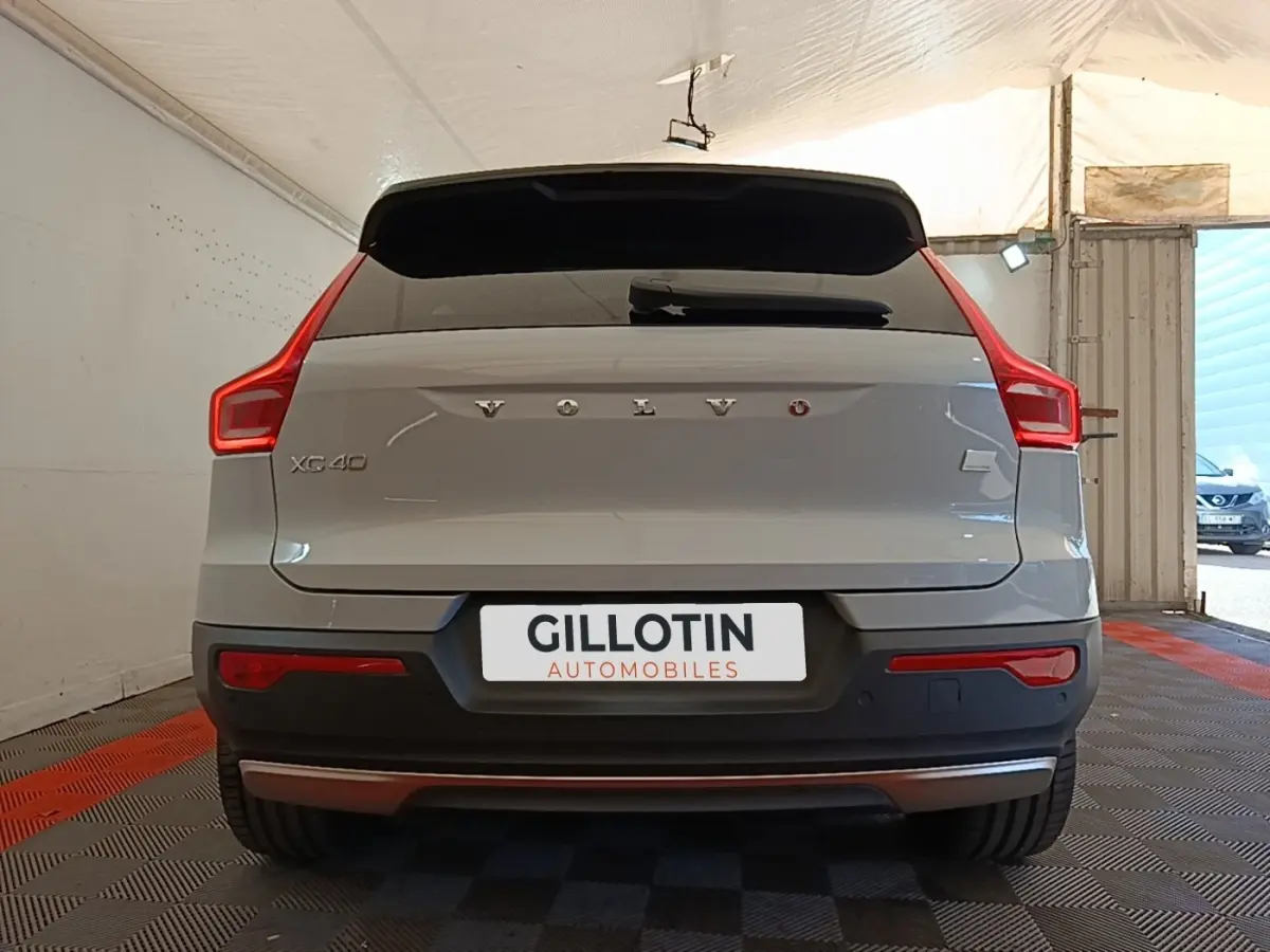 Vue arrière d'un Volvo XC40 gris clair électrique avec feux LED caractéristiques et logo centré sur le coffre.