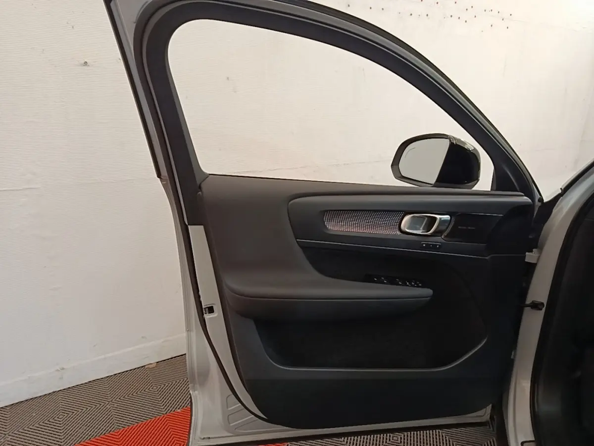 Vue intérieure de la porte avant gauche gris clair du Volvo XC40 P8 R-Design avec garniture noire et poignée métallique.
