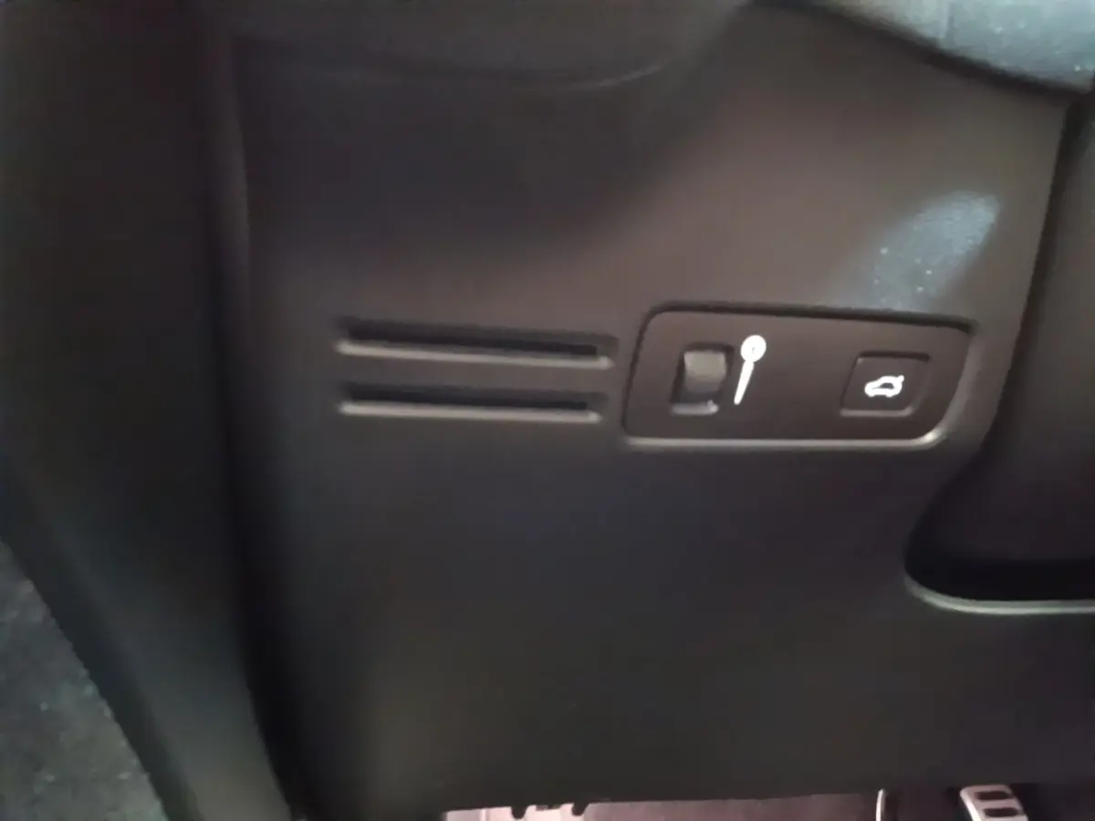 Détail intérieur noir du tableau de bord du Volvo XC40 P8 R-Design avec bouton ouverture coffre et levier de réglage.