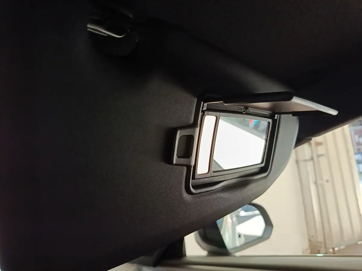 Miroir de courtoisie ouvert sur le pare-soleil côté conducteur dans l’habitacle gris du Volvo XC40 électrique.