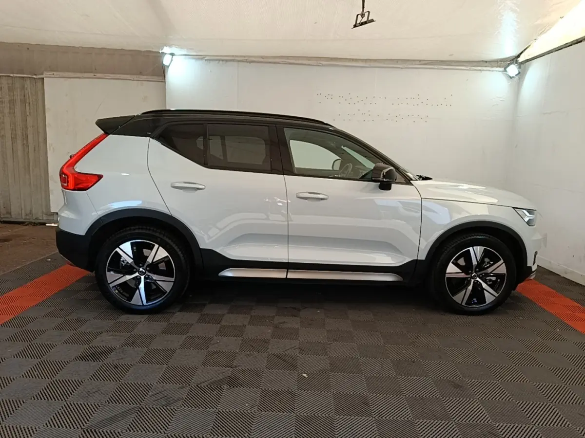 Vue de profil côté gauche d'un Volvo XC40 P8 R-Design gris clair avec toit noir et jantes alliage bicolores.