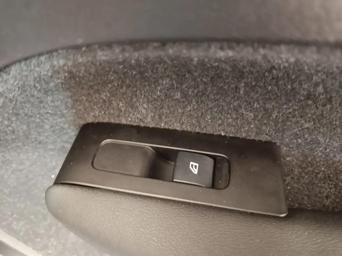 Gros plan sur le bouton de commande de lève-vitre électrique dans le coffre du Volvo XC40 P8 gris clair.