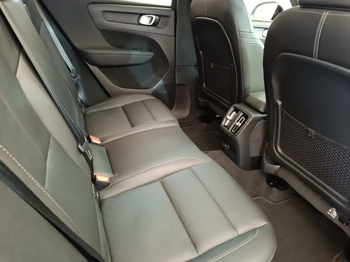 Vue intérieure arrière du Volvo XC40 P8 gris clair, montrant la banquette 3 places en cuir avec aérateurs centraux.