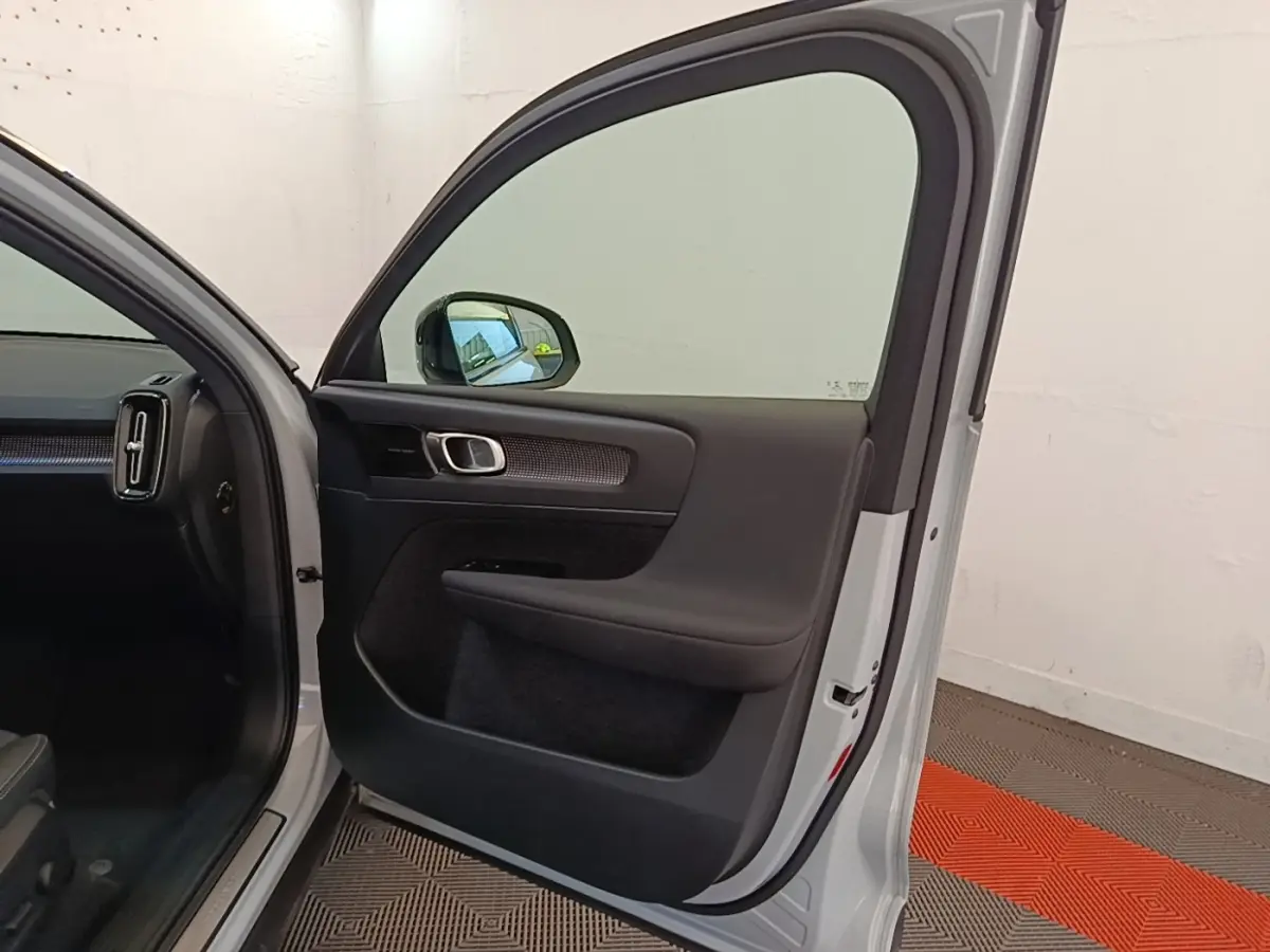 Vue intérieure de la porte avant gauche gris clair d’un Volvo XC40 P8 R-Design avec poignée alu et garniture noire.