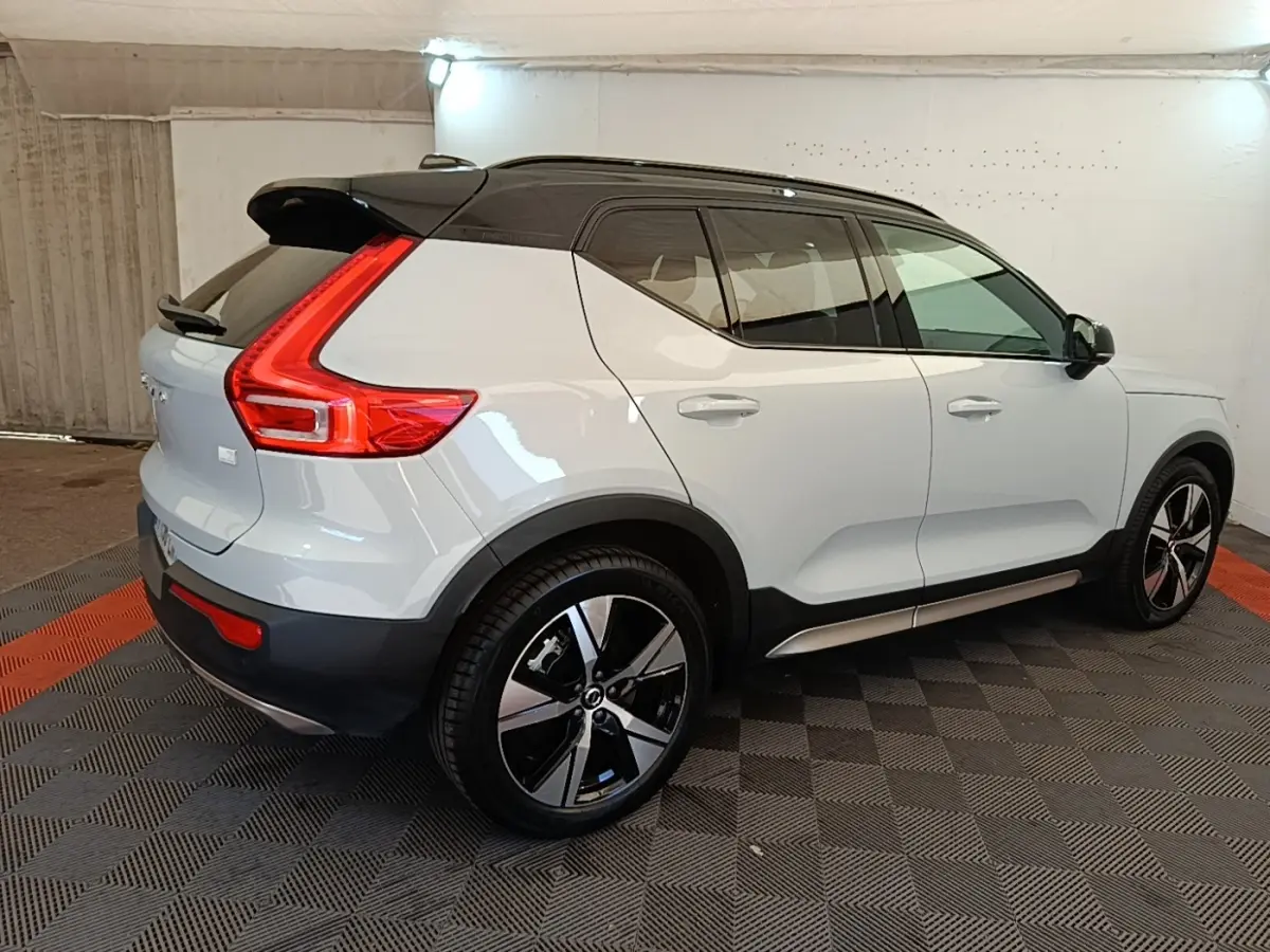Vue 3/4 arrière droite d'un Volvo XC40 gris clair avec toit noir et feux arrière en forme de L lumineux.