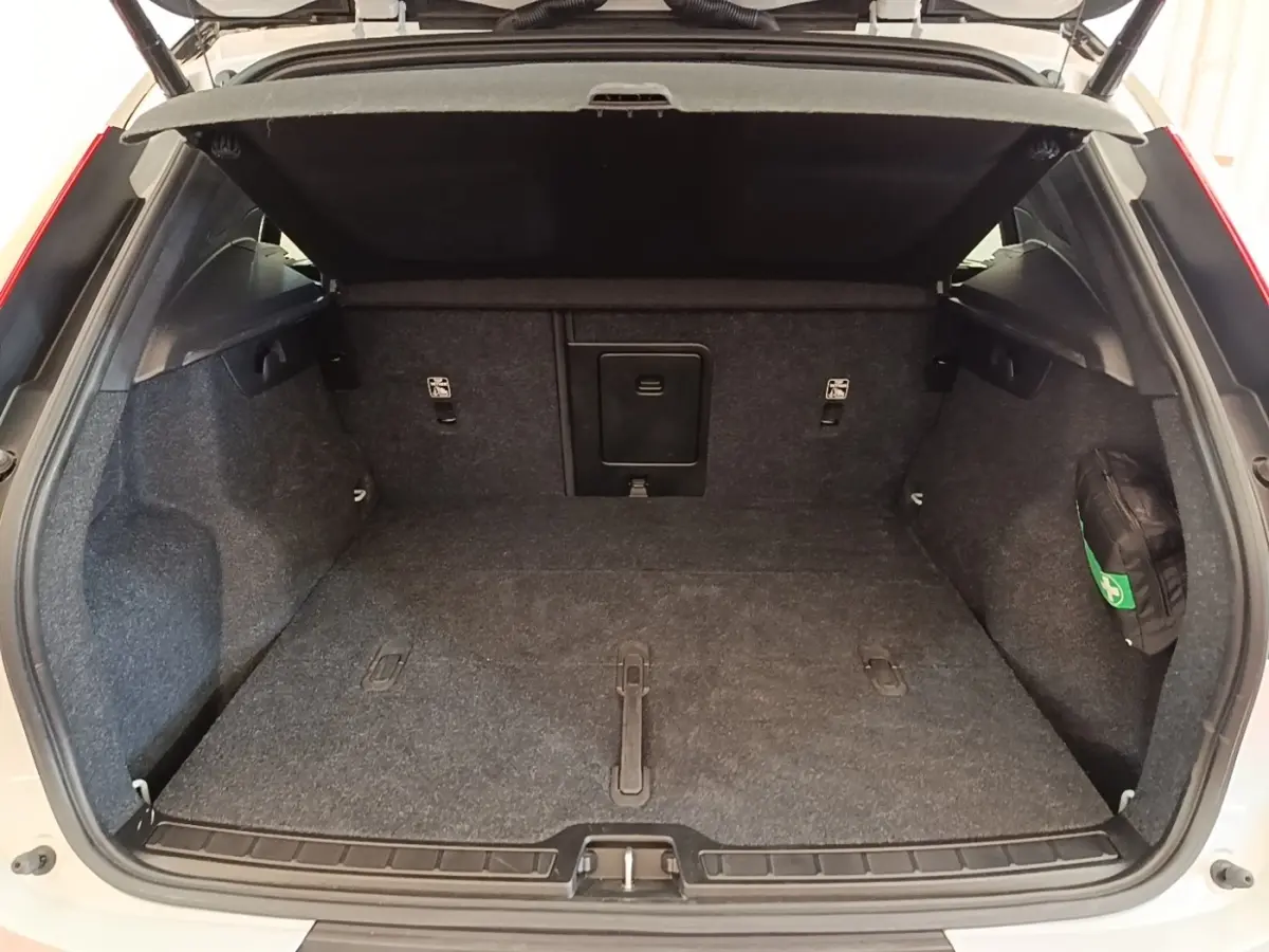 Coffre ouvert d’un Volvo XC40 gris clair, vue de l’arrière montrant un plancher plat et une banquette rabattable 2/3-1/3.
