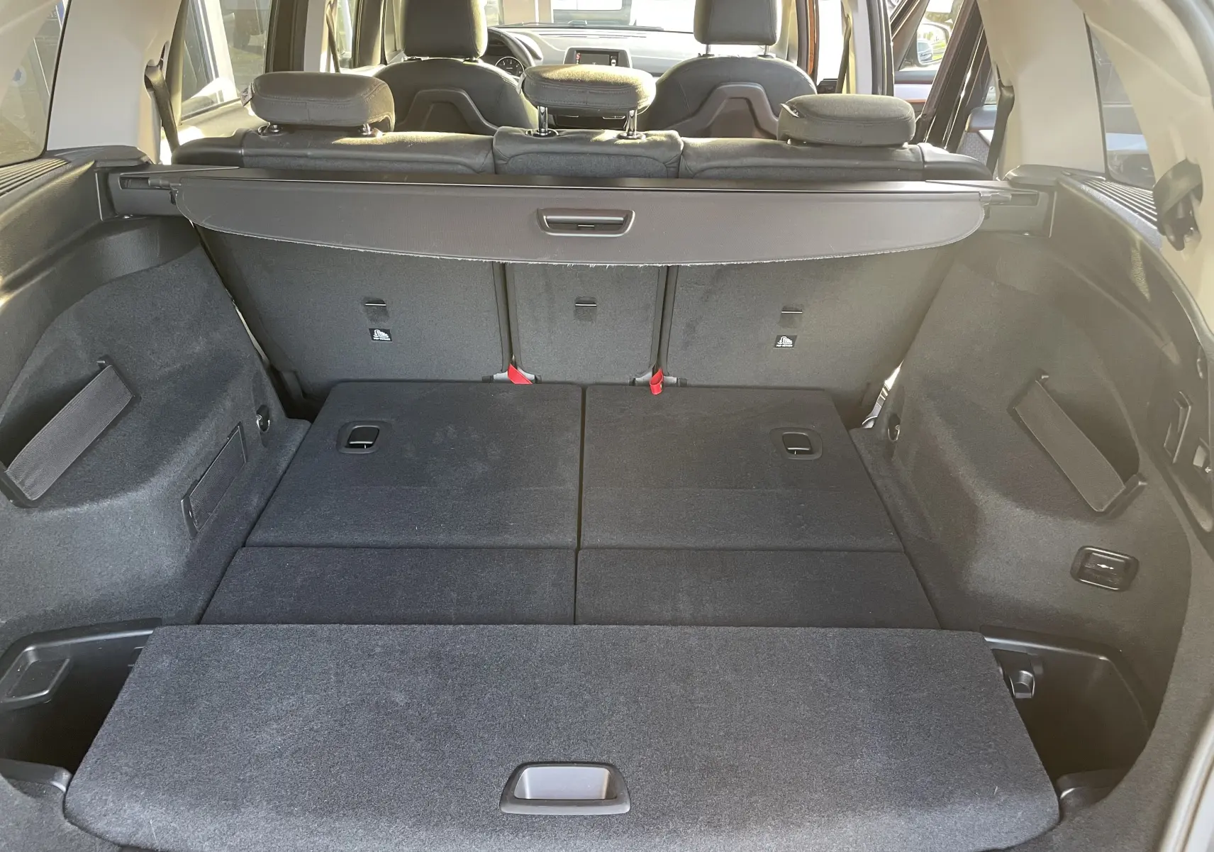 Coffre ouvert de la BMW Série 2 Gran Tourer 218d noire, vue arrière montrant les sièges arrière rabattus et l'espace de chargement.