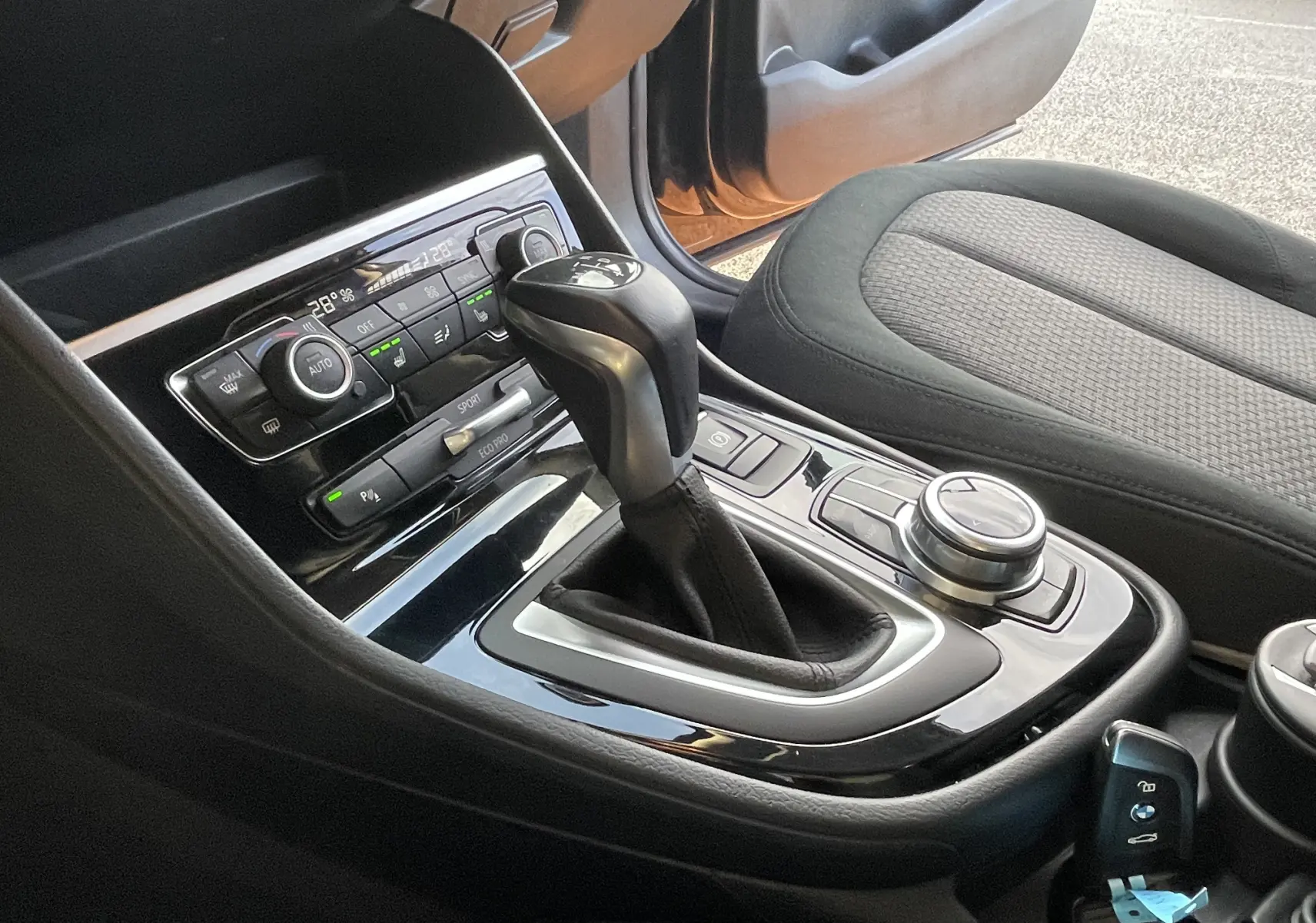 Gros plan sur la console centrale noire de la BMW Série 2 Gran Tourer F46 218 DA 150 Lounge avec levier de vitesses automatique.