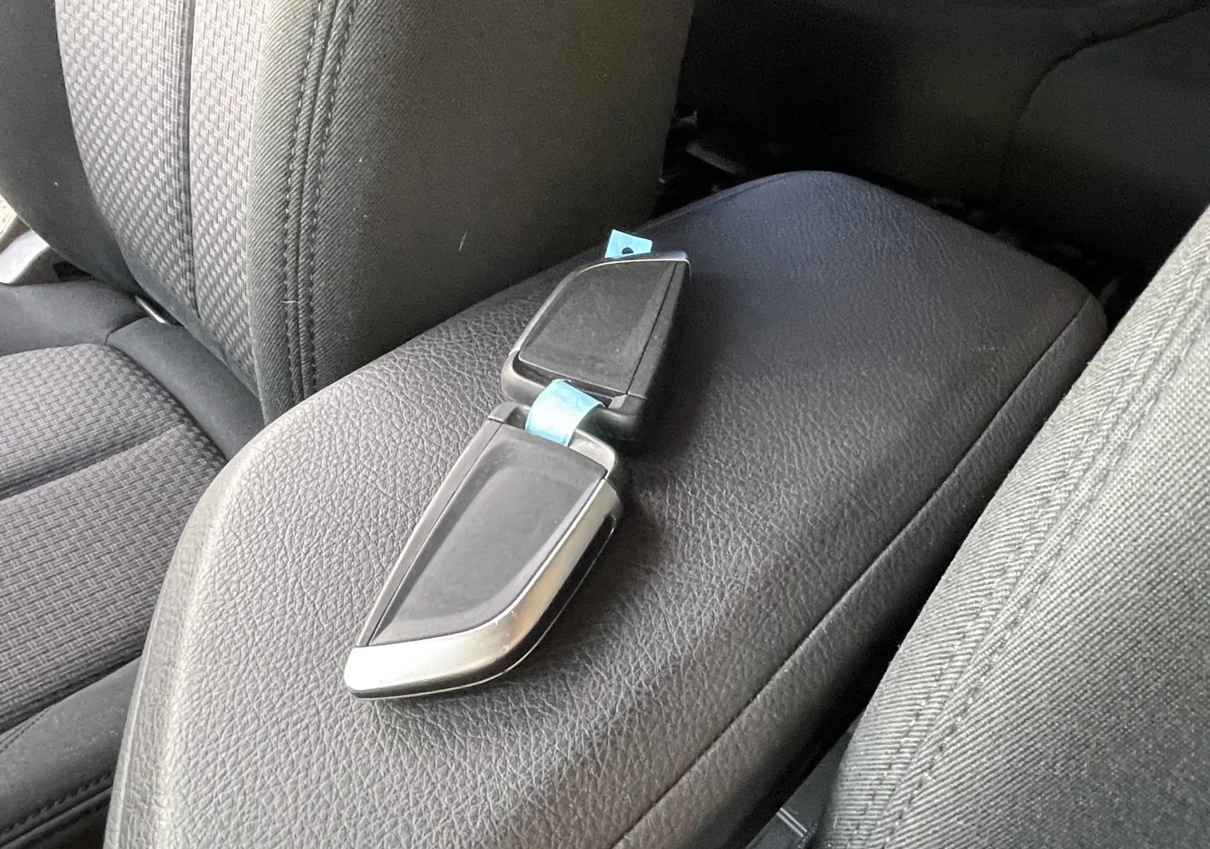 Clé BMW posée sur l'accoudoir central en cuir noir à l'intérieur d'une Série 2 Gran Tourer F46 218 DA 150 Lounge.