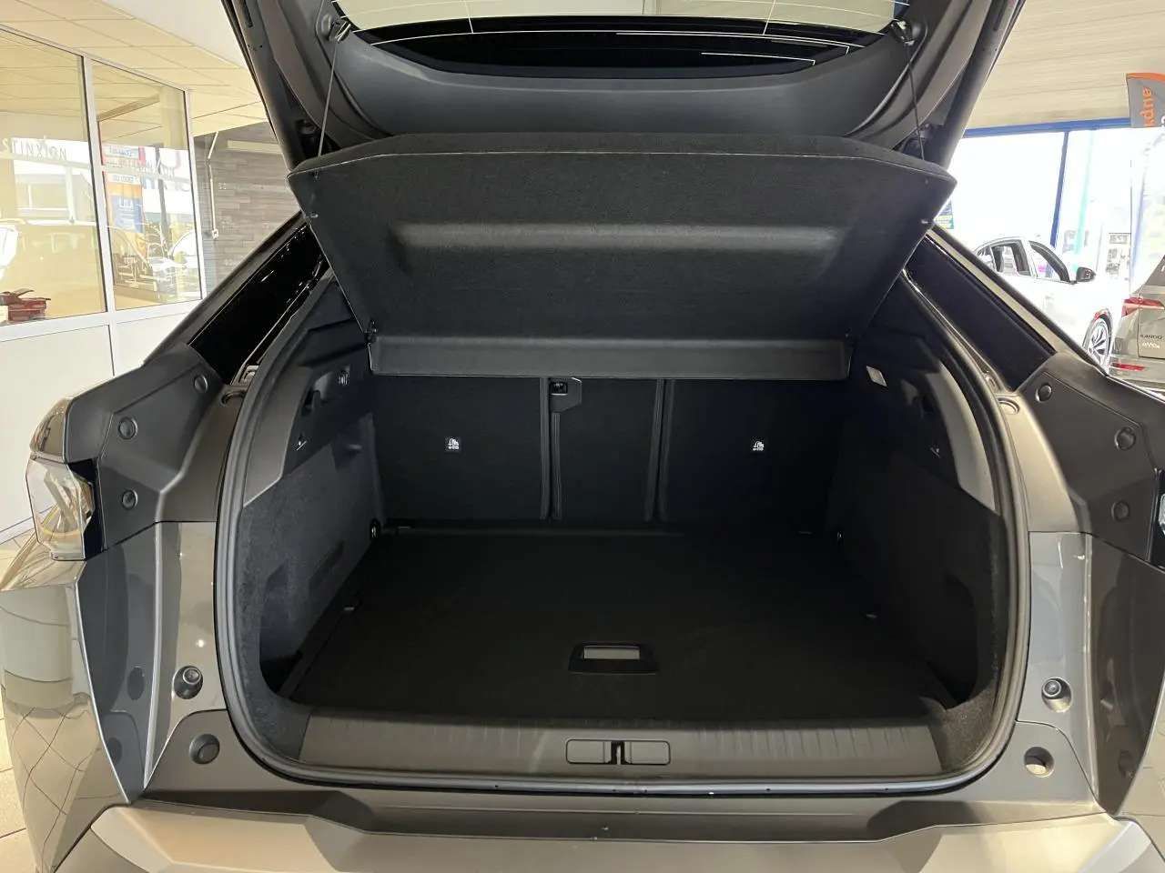 Coffre ouvert vu de l'arrière d'un Peugeot 3008 gris titanium avec intérieur noir dans un showroom.