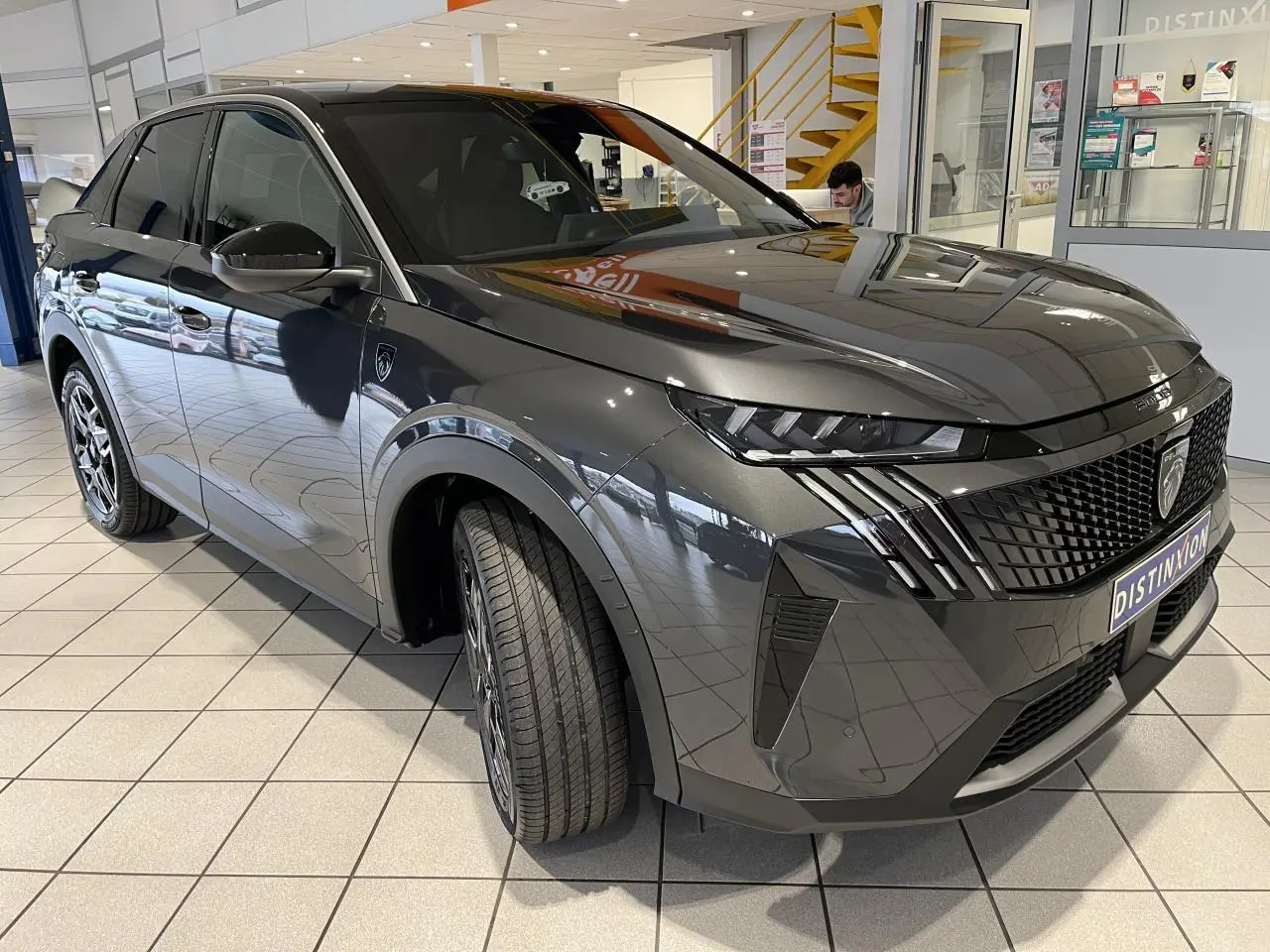 Peugeot 3008 gris titanium en 3/4 avant droit, avec calandre noire et feux LED griffés, en showroom.