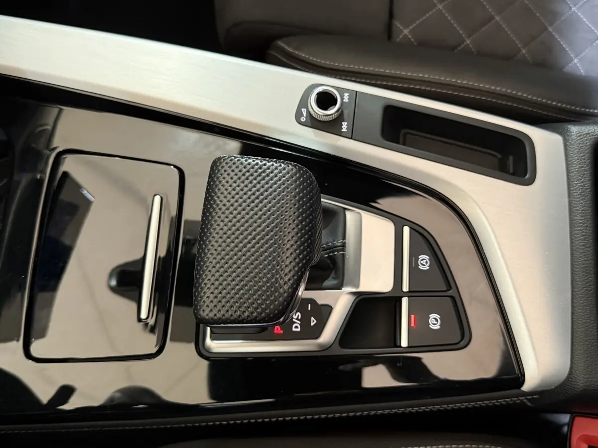 Gros plan sur la console centrale noire et argentée de l'Audi A4 35 TFSI avec levier de vitesse et commandes électroniques.