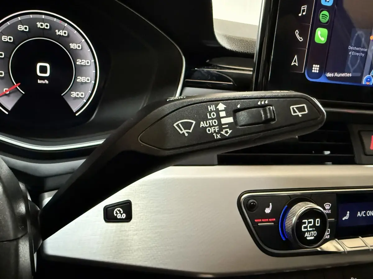 Gros plan sur la commande d’essuie-glace à gauche du volant dans l’habitacle de l’Audi A4 gris foncé, avec tableau de bord digital.