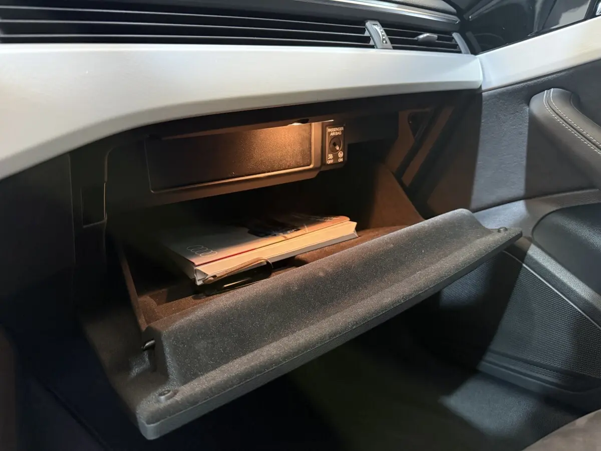 Gant de boîte à gants ouvert côté passager avec manuel Audi dans l’habitacle gris foncé d’une Audi A4 35 TFSI 2022.