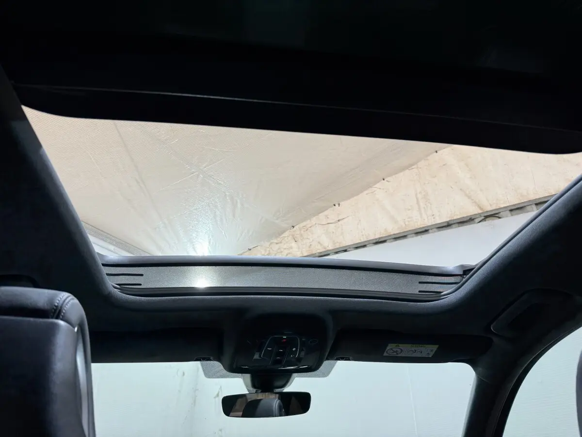 Vue intérieure du toit ouvrant panoramique de l'Audi A4 gris foncé, avec commandes intégrées au plafond.