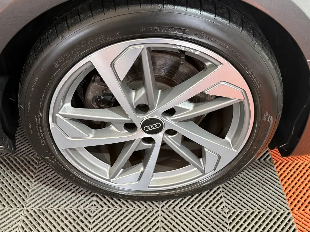 Gros plan sur la jante alliage argentée Audi Sport d’une Audi A4 gris foncé, vue côté droit.