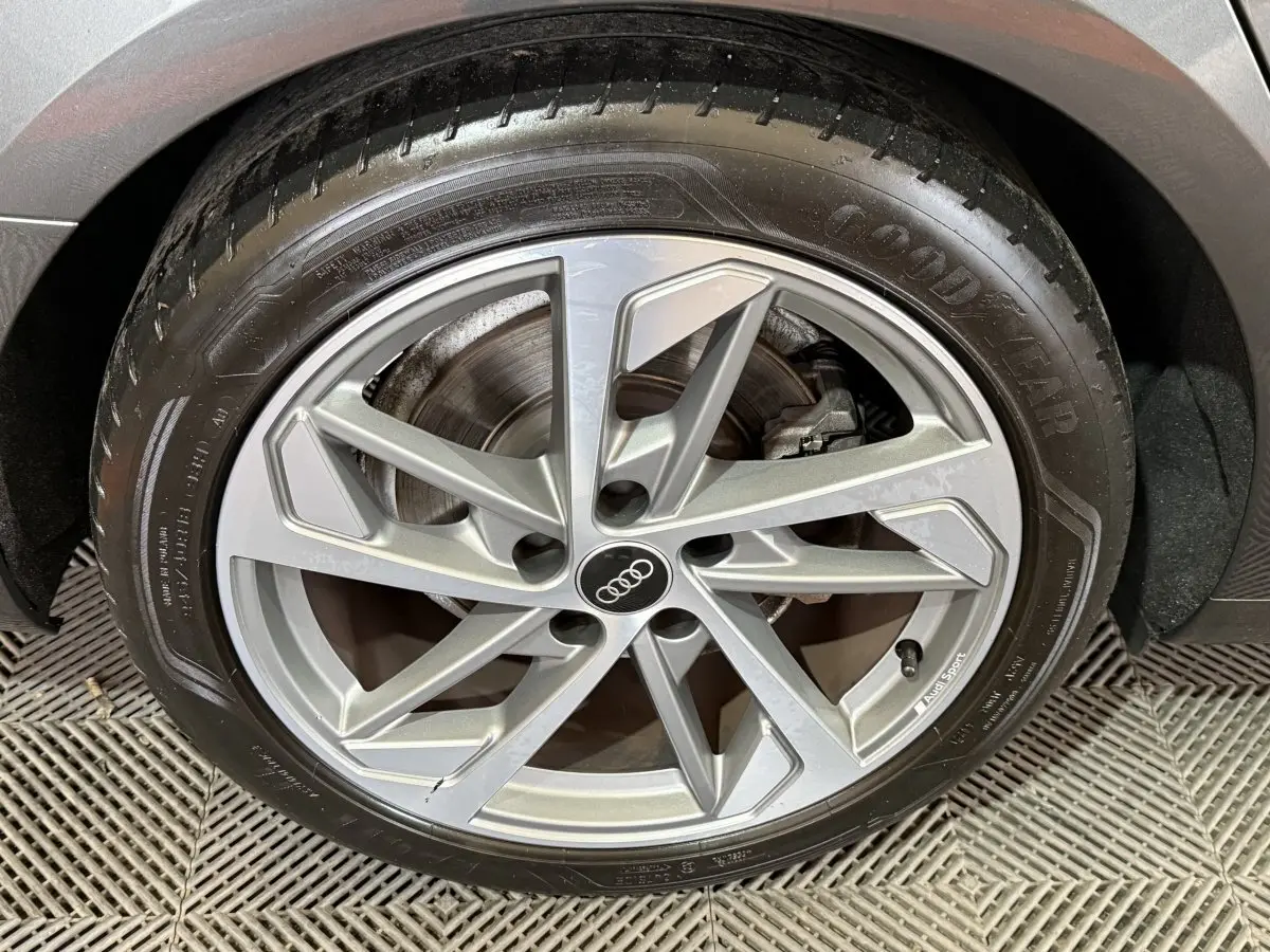 Gros plan sur la jante alliage argentée Audi Sport et pneu Goodyear d'une Audi A4 gris foncé, roue arrière droite.