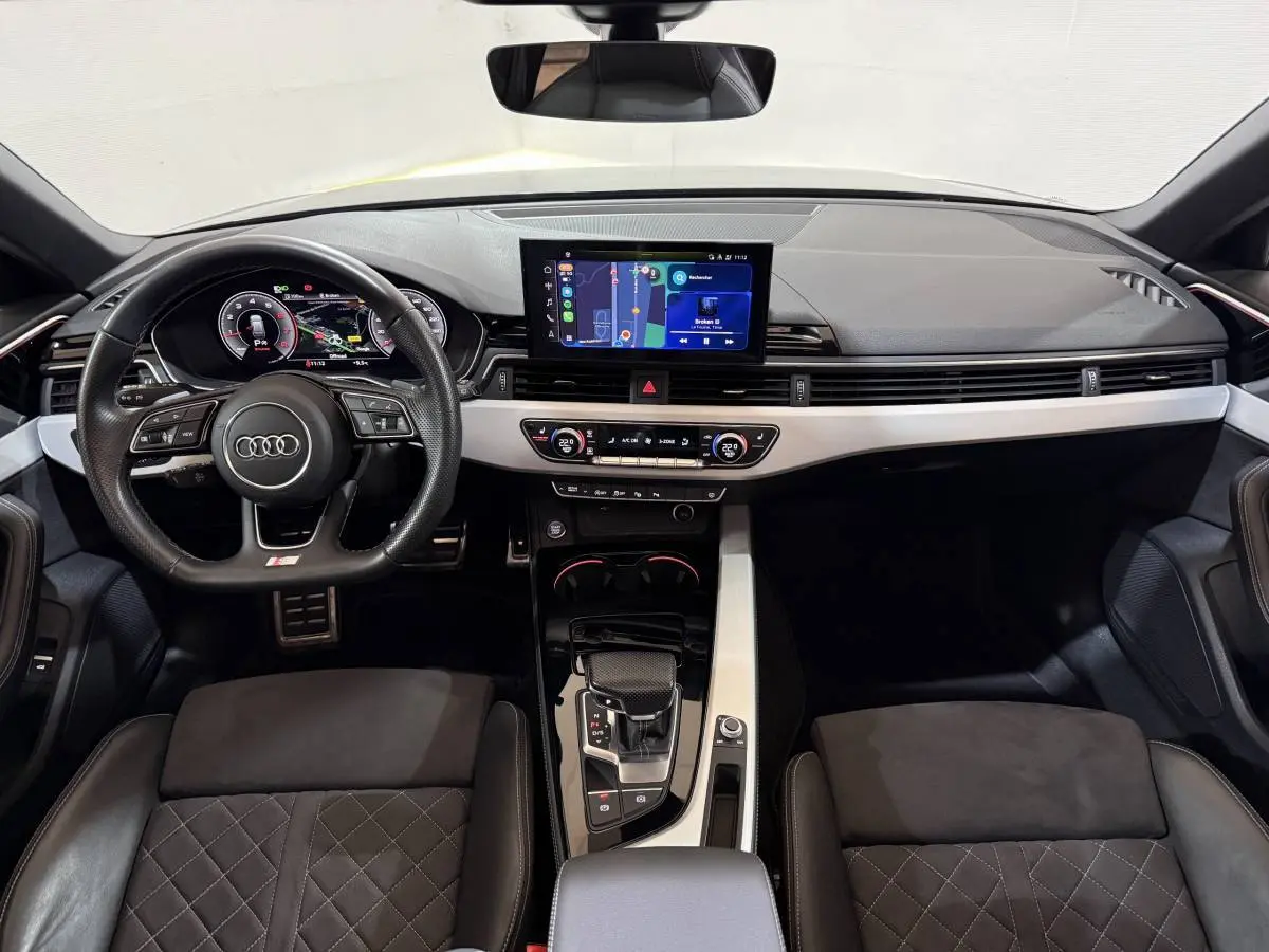 Vue intérieure avant de l'Audi A4 35 TFSI S Edition 2022, tableau de bord noir avec écran tactile central et volant cuir multifonctions.