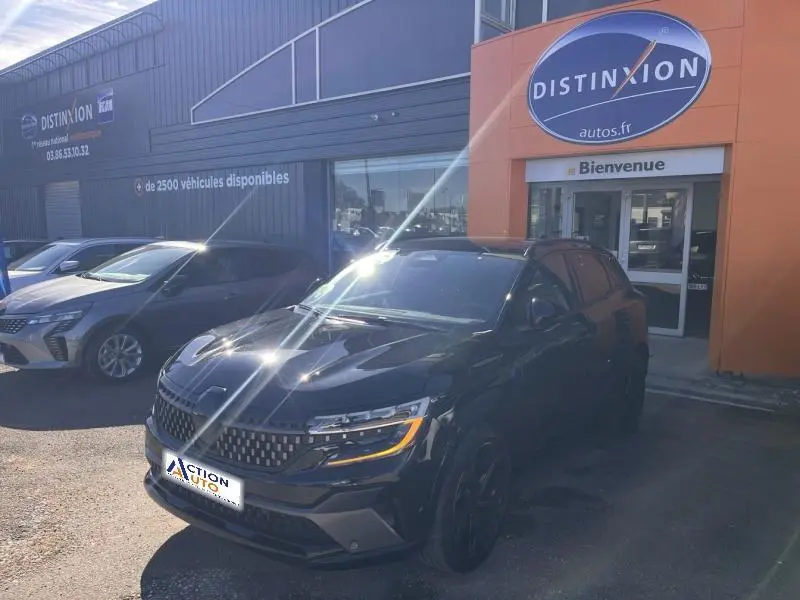 Vue 3/4 avant d'un Renault Austral noir étoilé garé devant un concessionnaire avec calandre et feux LED distinctifs.