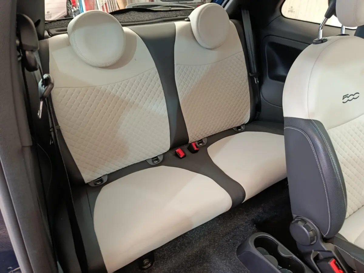 Vue intérieure sur la banquette arrière beige et noire de la FIAT 500 Hybrid 2022 avec appuie-têtes ronds.
